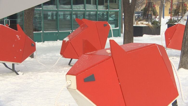 Blocky-shaped creatures coloured in red and white, with ropes connecting them, stand in the snow.