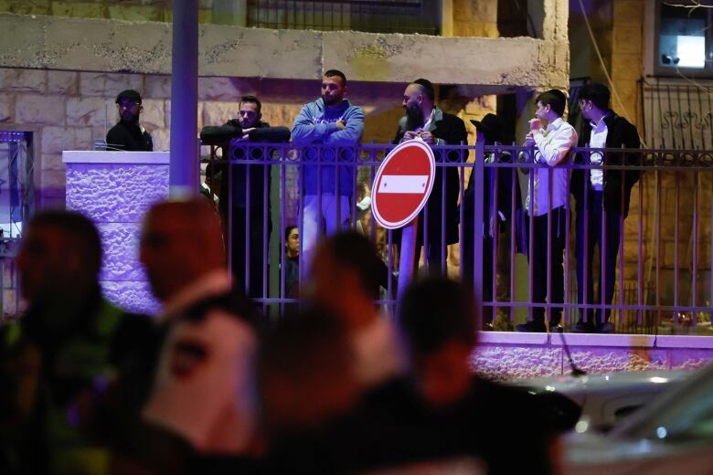 Onlookers are seen as police work in the foreground.