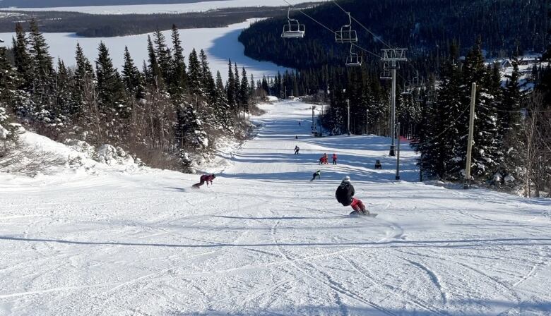 A group of snowboarders sliding down a snow covered hill. 