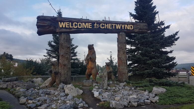 A log carving of a bear and carved sign reading 'Welcome to Chetwynd.'