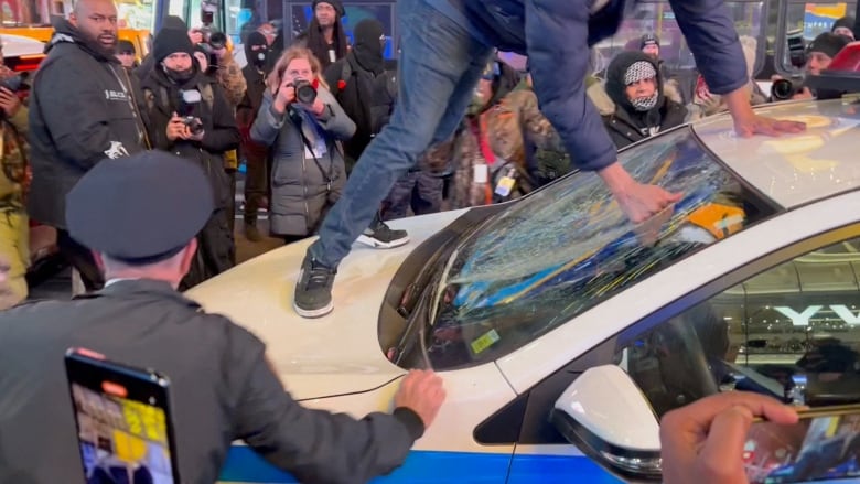 Police approach a man who jumped on a police car.