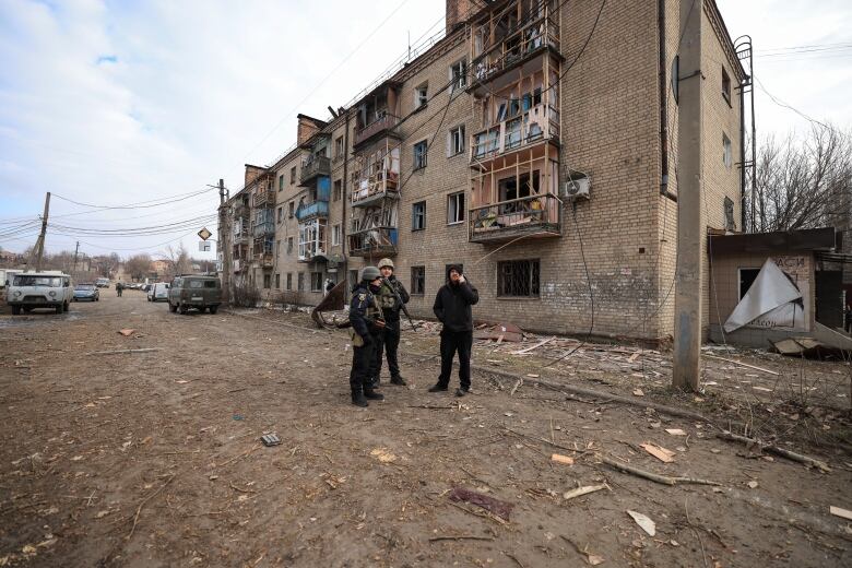 Police officers stand in front of a building in Kostyantynivka, Ukraine, which was damaged in a Russian missile attack.