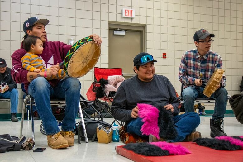 Men play a traditional Indigenous game with moccasins on the floor.