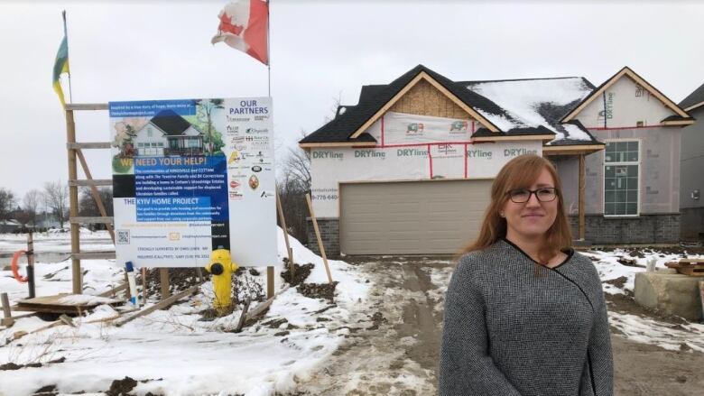 A woman standing in front of a house under construction