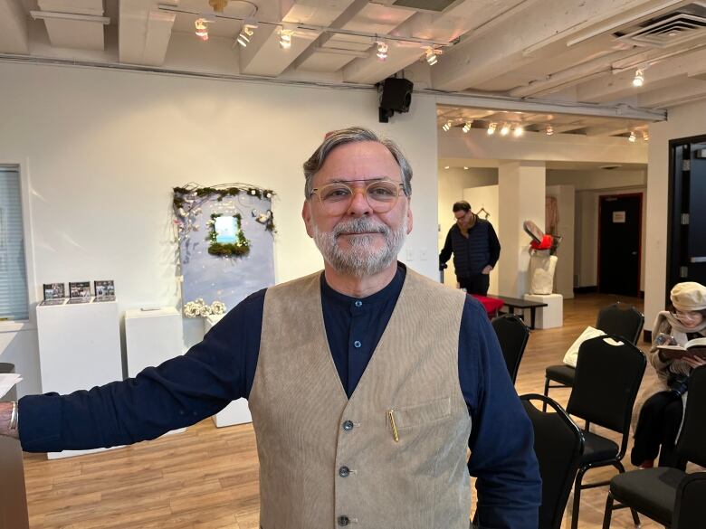 A man standing in an art gallery smiling. 