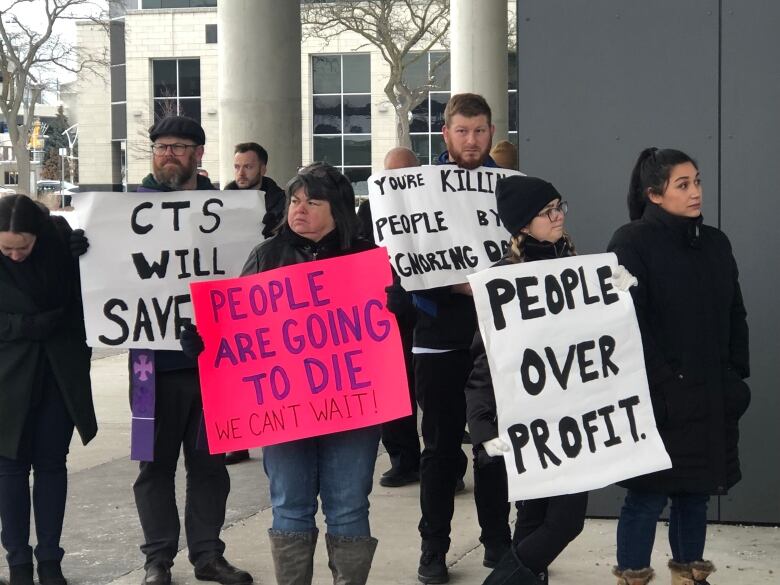 people holding up signs, in support of the CTS coming to downtown Windsor