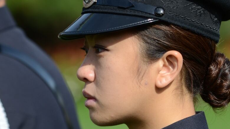 A woman wearing a police uniform looks solemn.