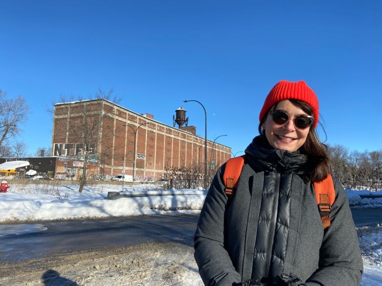 Woman standing in front of an old brick industrial building