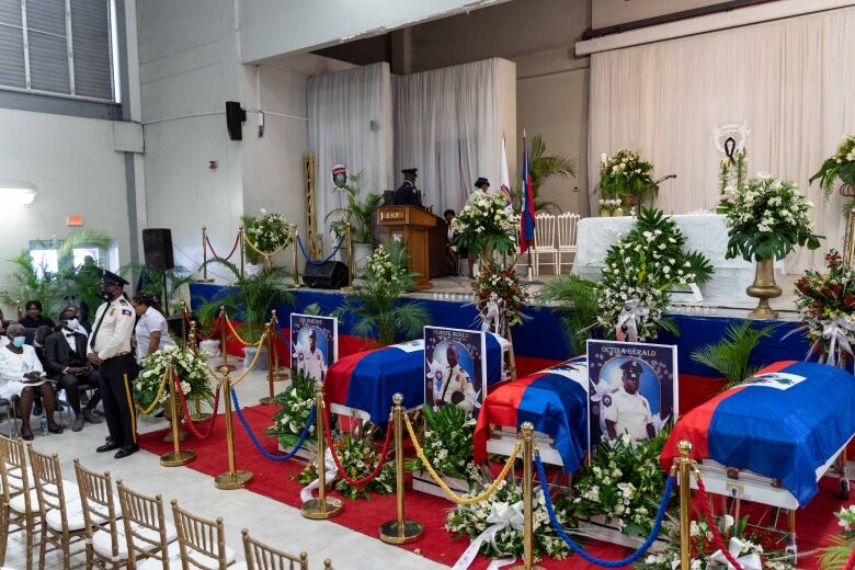 Draped coffins, flowers and empty chairs are shown as a service begins.