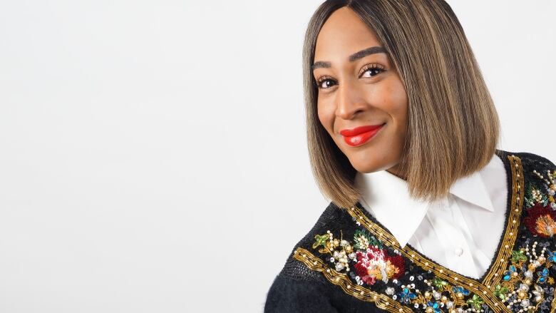 A head-and-shoulders shot of a smiling Black woman with straight, shoulder-length hair and a black sequin top