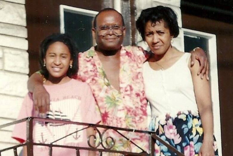 A girl and her parents stand at their front door.