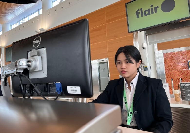 A person works on a computer at an airport desk.