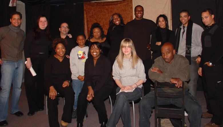 A director and her cast sit and stand for a photo. 