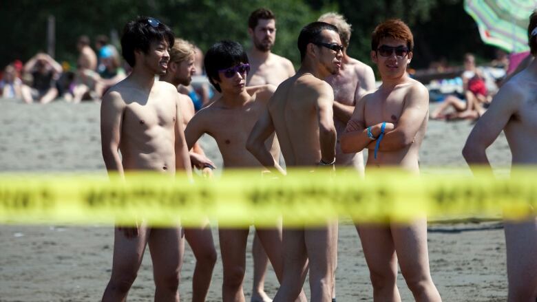 Nude beachgoers stand around at Vancouver's Wreck Beach.