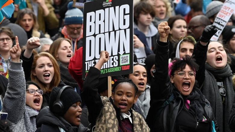 A group of young strikers in Britain raise fists and shake signs.