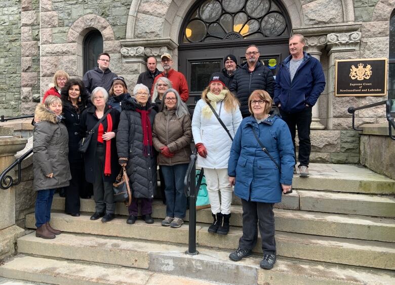 About 16 people stand on the steps of the Newfoundland and Labrador Supreme Court.