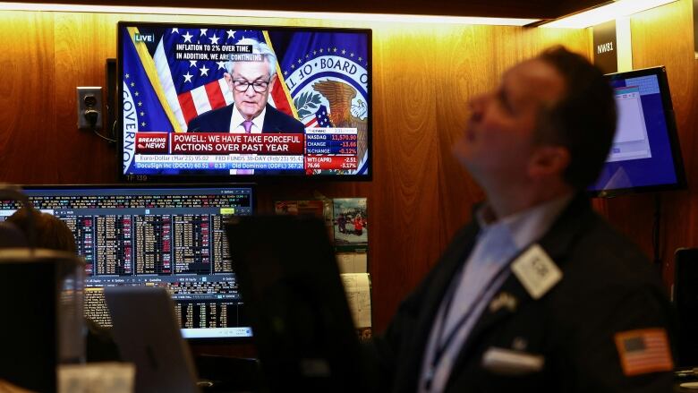 A trader works on the floor of the New York Stock Exchange (NYSE) as a screen shows Federal Reserve Board Chairman Jerome Powell during a news conference following a Fed rate announcement, in New York City, U.S., February 1, 2023. REUTERS/Andrew Kelly