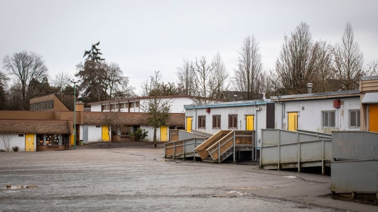 A low-slung group of single-storey buildings rings an empty lot.