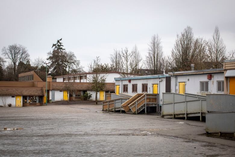 A low-slung group of single-storey buildings rings an empty lot.