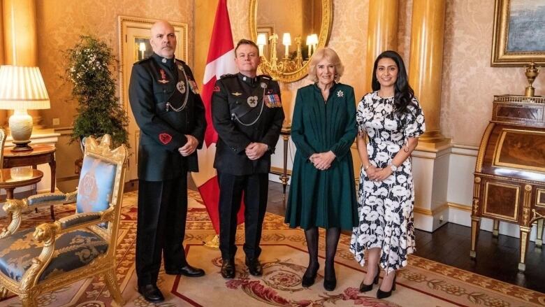 Two men in the military, in uniform, stand beside Queen Consort Camilla and Calgary entrepreneur Manjit Minhas at Buckingham Palace.