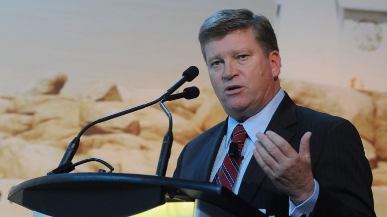 A PHOTOGRPH OF TOM CLARK SPEAKING AT A PODIUM