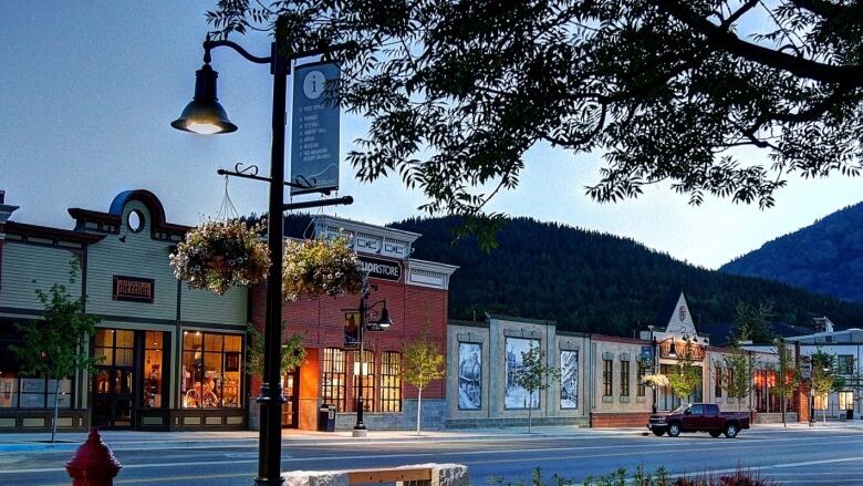 An array of shops on the street, with a hill on the background and a lamp post on the front.