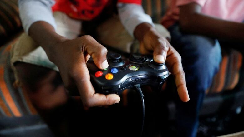 A 13-year-old boy holds a video game controllers in his hands.