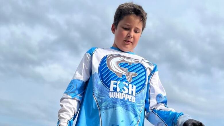 A boy wearing a rubber glove and holding a small fish.