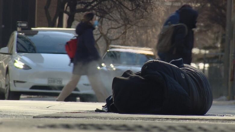 A person is seen sleeping on the street in downtown Toronto on Feb. 3, 2023 amid an extreme cold warning that sent the city into a deep freeze.