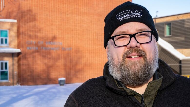 A man wears a toque standing in the cold.