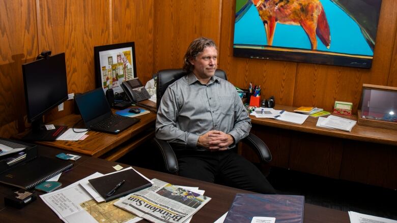 A man sits at a desk looking to the right.