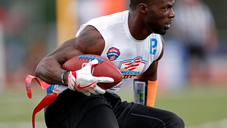 A flag-football player carries the ball in his right arm.