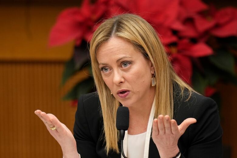 Italian Prime Minister Giorgia Meloni gestures with her hands as she gives an interview.