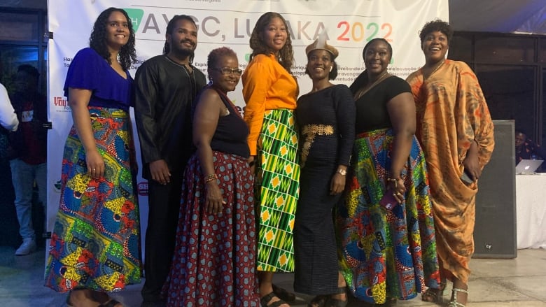 A group of seven people in traditional African dress pose for the camera.