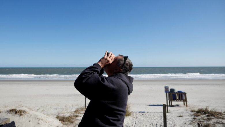 A person looks at the sky with binoculars.