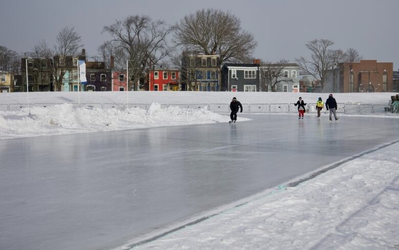 Four people are seen skating on a skate track.