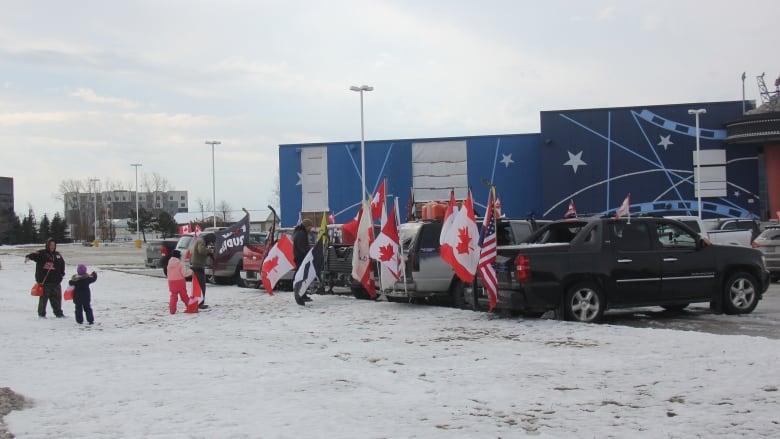 Parked trucks with Canadian and American flags waving from the back of the trucks