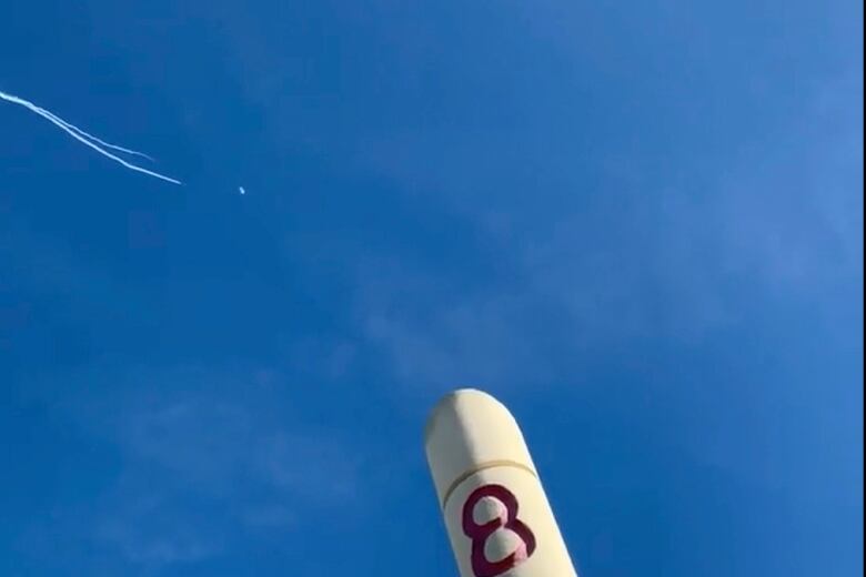 Trails of white smoke are seen in blue sky.