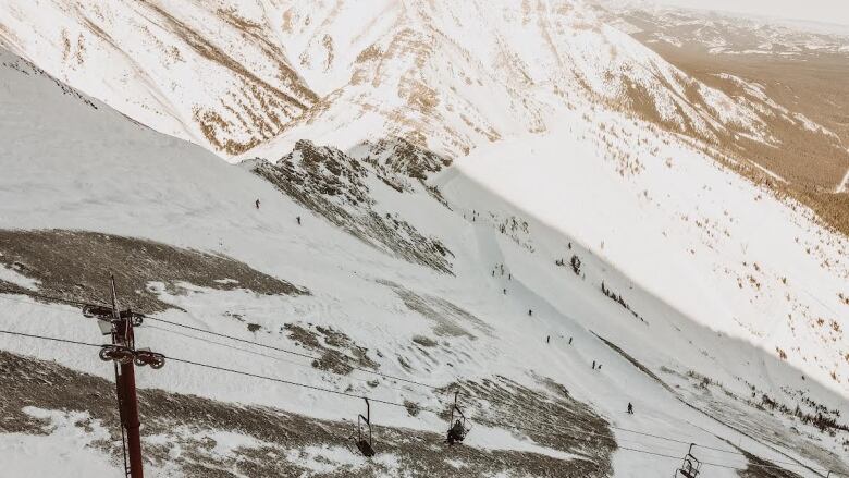 a snowy mountain is seen here with a ski lift in the foreground 