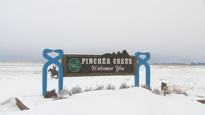 a sign that reads pincher creek welcomes you sits in a snowy field