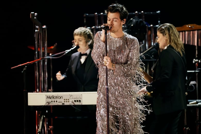 A man in a shiny suit sings on stage.