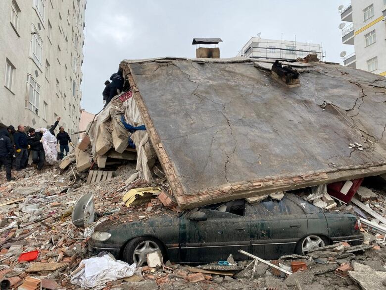 People search through rubble below a collapsed roof of a building following a powerful earthquake.