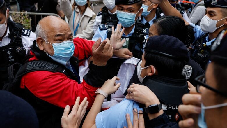 At a court building in Hong Kong, a supporter of pro-democracy activists scuffles with police officers.