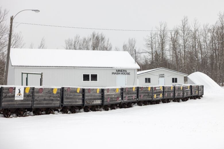 Coal carts sit in the snow at the Springhill Miners Museum next to the miners wash house and lamp cabin.