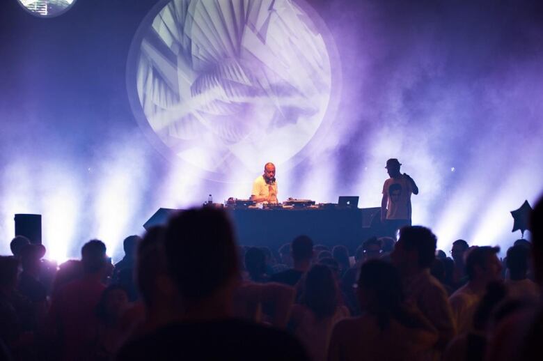 A DJ plays records on stage in front of a crowd.