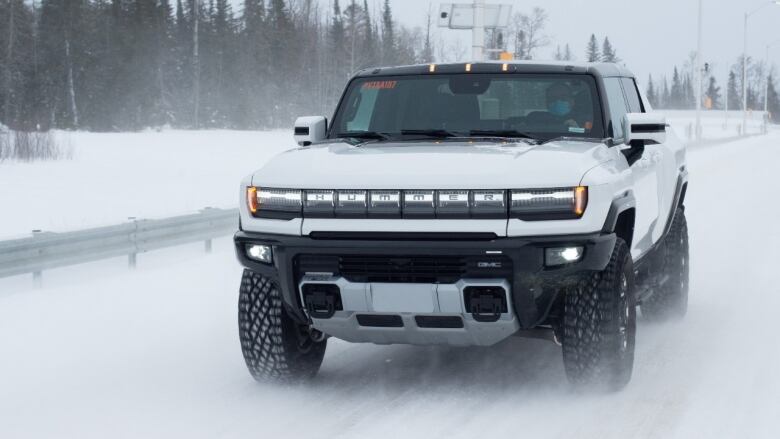 A man driving a large white vehicle in the snow.