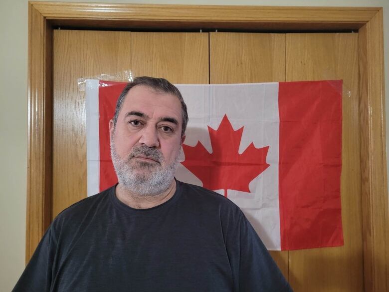 A man stands in front of a Canadian flag.