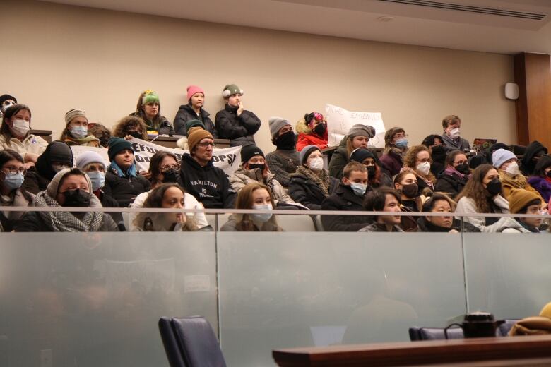 About 40 protesters sit in a gallery listening to councillors. 