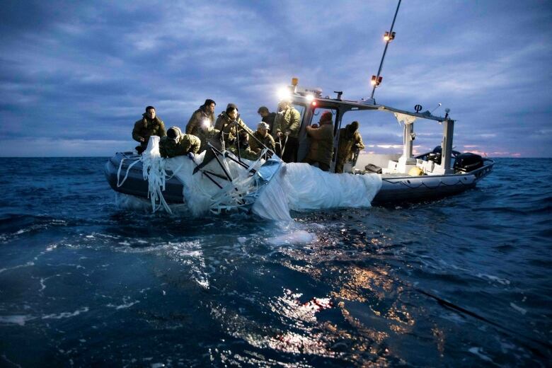 The 8-person crew pulls the white fabric further up onto the boat