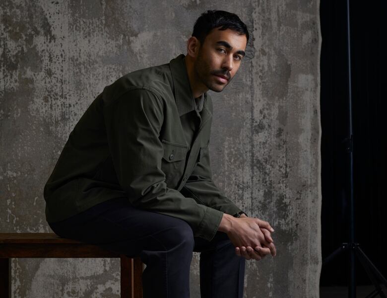 Antoine Bourges sitting and leaning forward against a concrete-style backdrop.